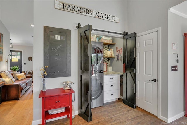washroom with laundry area, baseboards, and light wood-type flooring