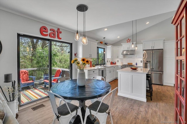 dining space with visible vents, light wood-style flooring, lofted ceiling, and a wealth of natural light