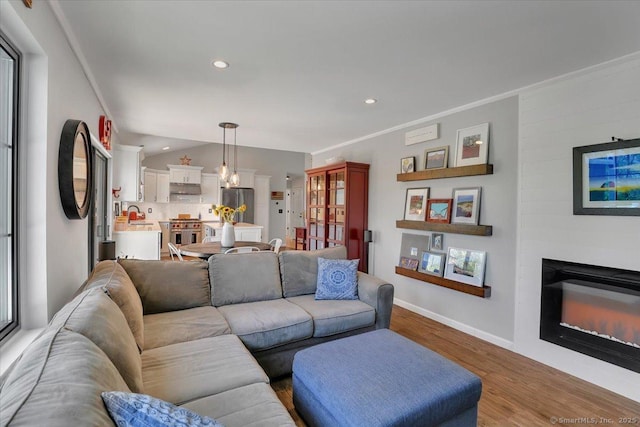 living area with recessed lighting, baseboards, a glass covered fireplace, and wood finished floors