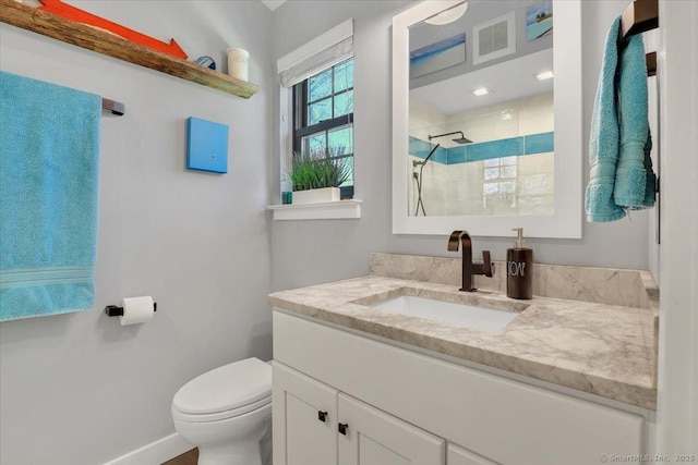 full bathroom featuring vanity, toilet, baseboards, visible vents, and tiled shower