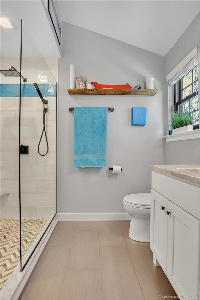 full bath featuring a tile shower, vanity, toilet, tile patterned floors, and baseboards