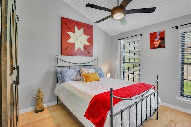 bedroom featuring baseboards, multiple windows, wood finished floors, and lofted ceiling