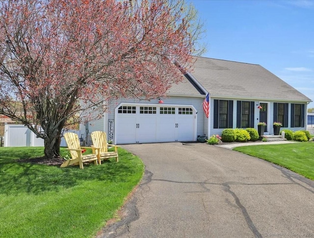 ranch-style house featuring a shingled roof, an attached garage, driveway, and a front yard