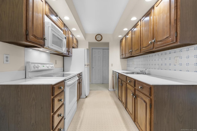kitchen with white appliances, a sink, recessed lighting, light countertops, and backsplash