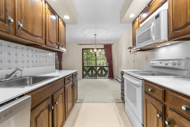 kitchen featuring white appliances, a sink, light countertops, recessed lighting, and baseboard heating