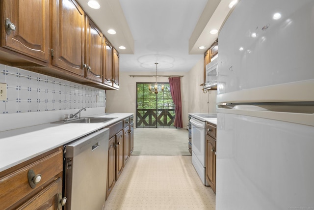 kitchen featuring white appliances, a sink, recessed lighting, light countertops, and decorative light fixtures