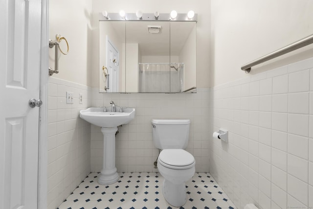 bathroom featuring toilet, a wainscoted wall, and tile walls