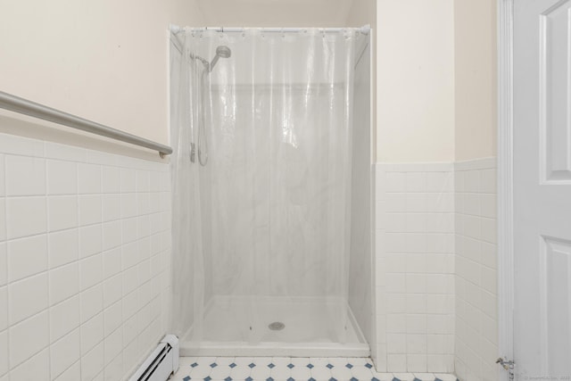 bathroom featuring tile walls, a shower stall, and wainscoting