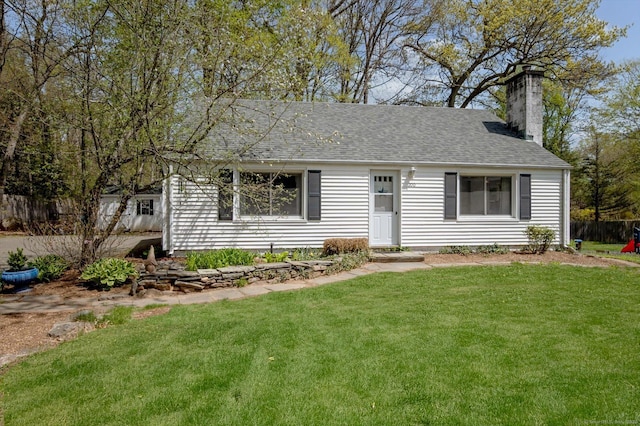 view of front of house featuring fence, a chimney, roof with shingles, and a front lawn