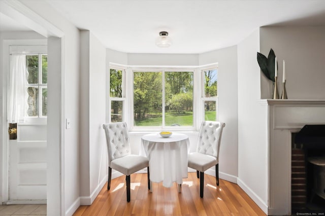 dining space featuring baseboards, a fireplace, light wood finished floors, and a wealth of natural light