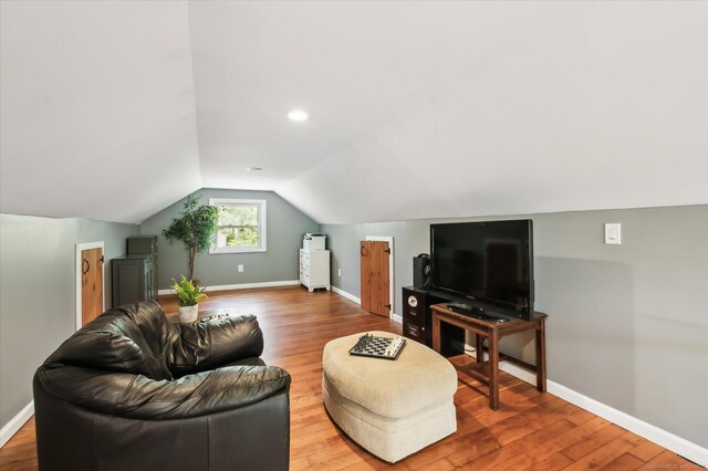 living area featuring baseboards, vaulted ceiling, and wood finished floors