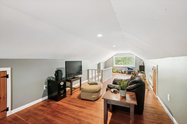 living area featuring baseboards, lofted ceiling, and hardwood / wood-style flooring