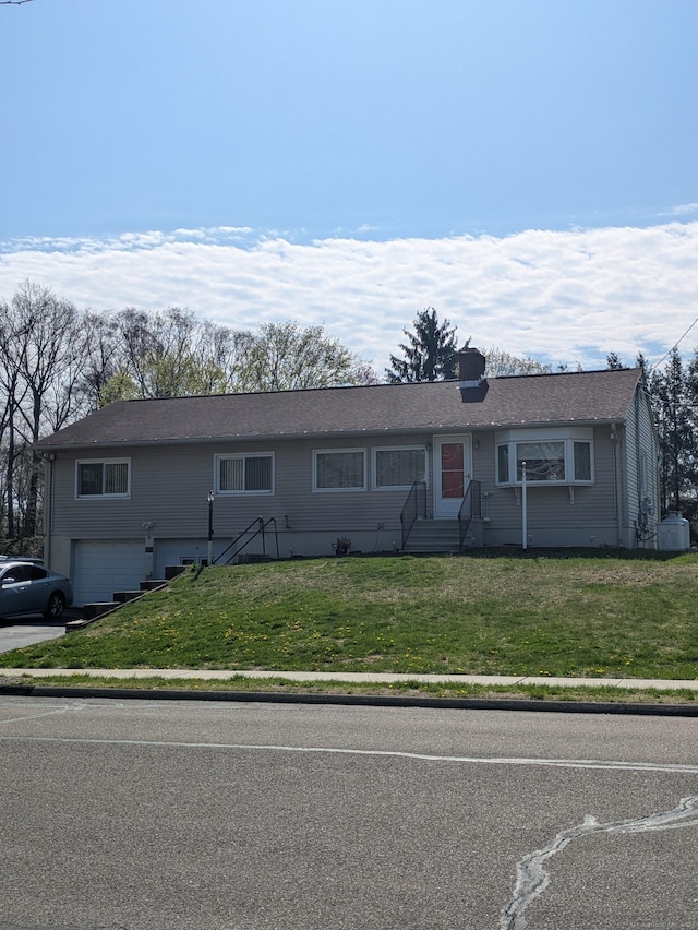 ranch-style home featuring an attached garage, a front lawn, a chimney, and entry steps