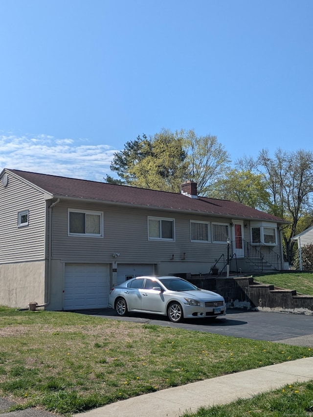 view of front of home with a garage, a chimney, a front lawn, and aphalt driveway