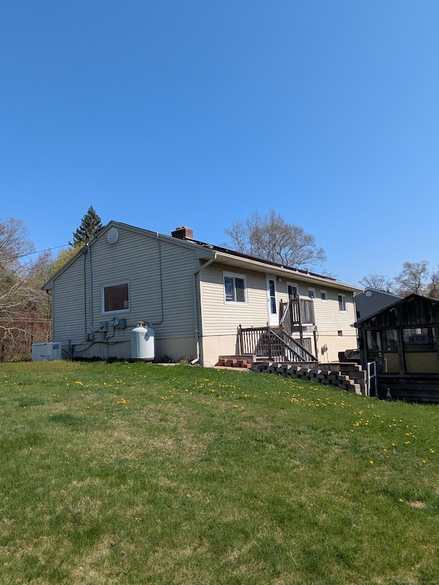 rear view of house featuring a yard, a chimney, and a sunroom