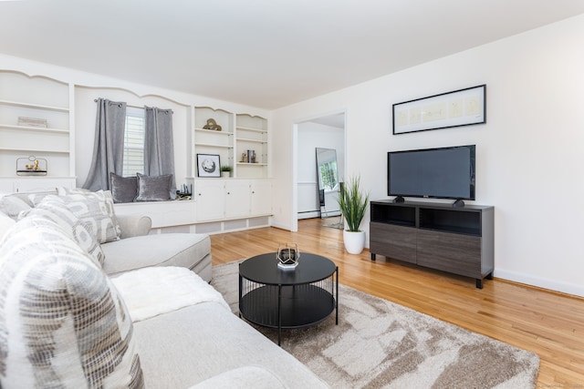 living area featuring light wood-type flooring, a baseboard radiator, and baseboards