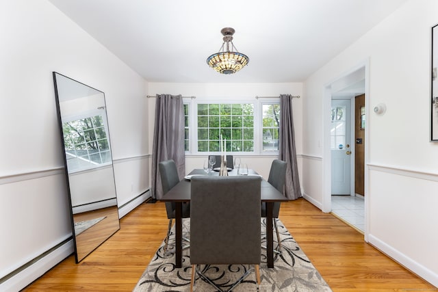dining space with baseboard heating, plenty of natural light, and light wood-style flooring