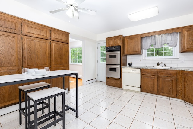kitchen featuring dishwasher, double oven, a sink, and brown cabinetry