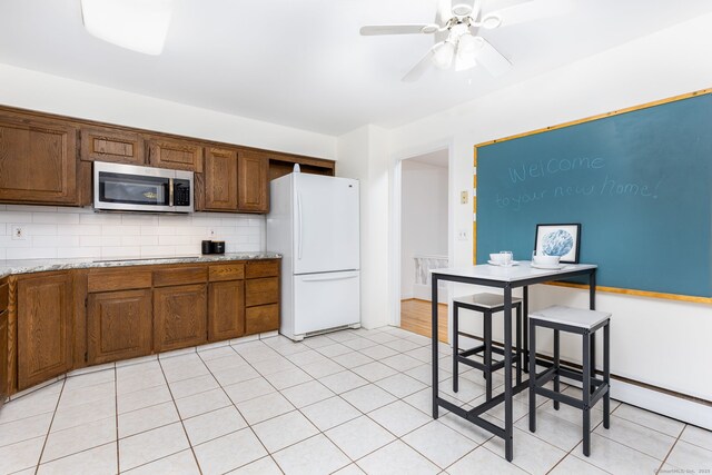kitchen featuring stainless steel microwave, freestanding refrigerator, electric stovetop, ceiling fan, and backsplash