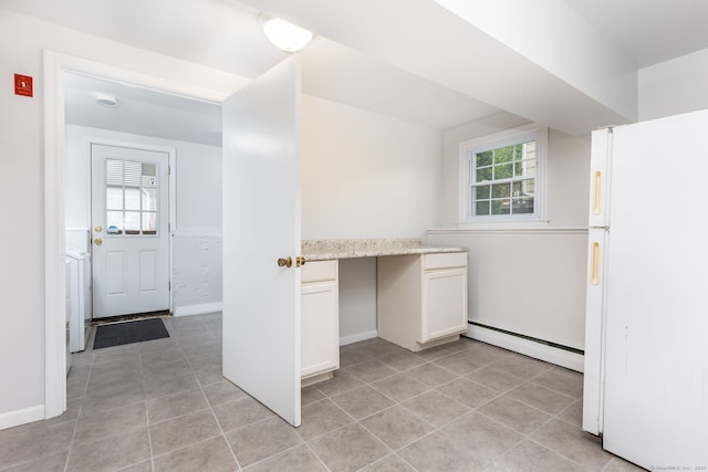 interior space with baseboard heating, freestanding refrigerator, healthy amount of natural light, and white cabinets