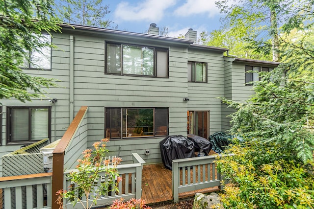 back of property with a chimney and a deck