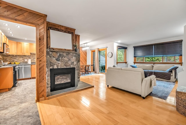 living area featuring a stone fireplace, light wood finished floors, and recessed lighting