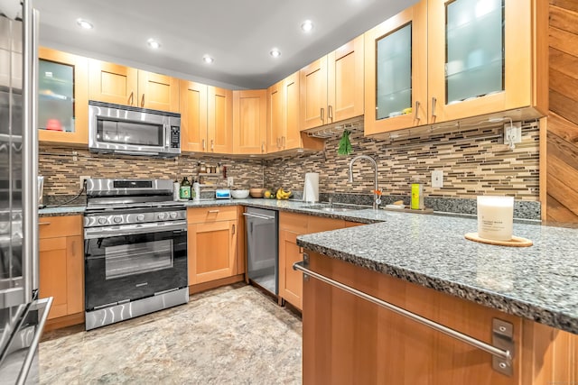 kitchen featuring dark stone counters, appliances with stainless steel finishes, and a sink