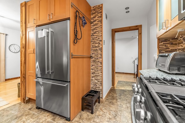 kitchen featuring baseboards, a toaster, tasteful backsplash, and appliances with stainless steel finishes