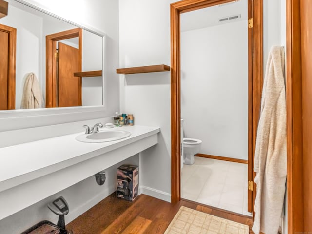bathroom featuring toilet, baseboards, visible vents, vanity, and wood finished floors