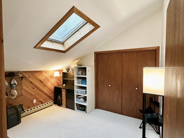 bonus room featuring carpet flooring, a baseboard radiator, wooden walls, and vaulted ceiling with skylight