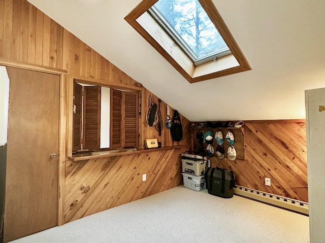 additional living space with wood walls, a baseboard radiator, lofted ceiling with skylight, and carpet floors