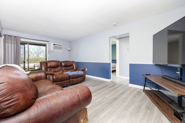 living room featuring baseboards, a wall mounted AC, and light wood-style flooring