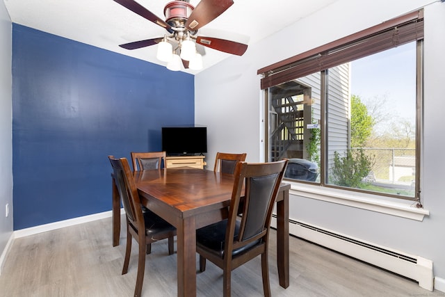 dining area featuring baseboards, ceiling fan, wood finished floors, and a baseboard radiator