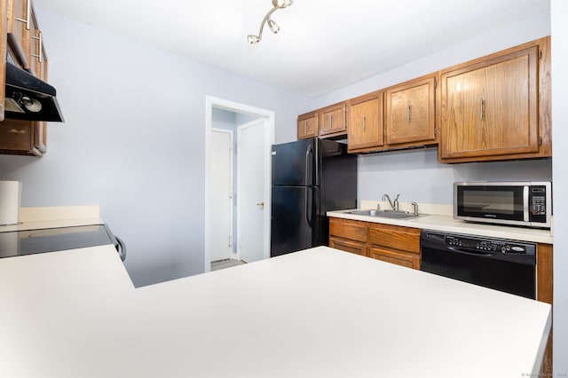 kitchen featuring a sink, light countertops, brown cabinetry, under cabinet range hood, and black appliances