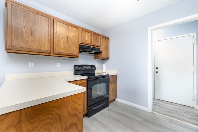kitchen with brown cabinetry, black electric range oven, light countertops, light wood finished floors, and under cabinet range hood