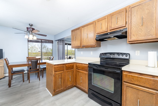 kitchen with a peninsula, black electric range oven, light countertops, under cabinet range hood, and light wood-style flooring