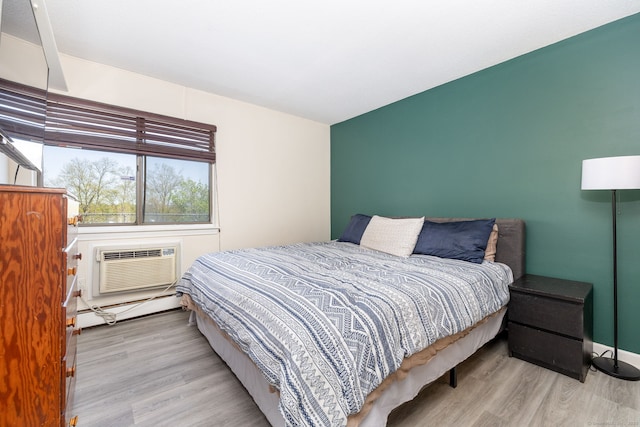 bedroom featuring a baseboard heating unit, wood finished floors, and a wall mounted air conditioner