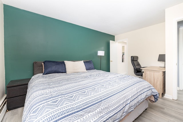 bedroom featuring baseboards, a baseboard radiator, and wood finished floors