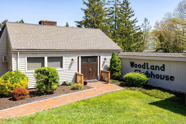 cape cod home with roof with shingles, a chimney, and a front yard