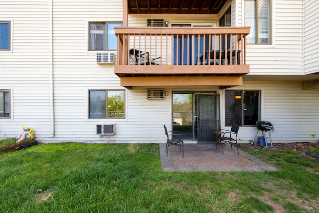 back of house with a lawn, a patio area, a wall unit AC, and a balcony