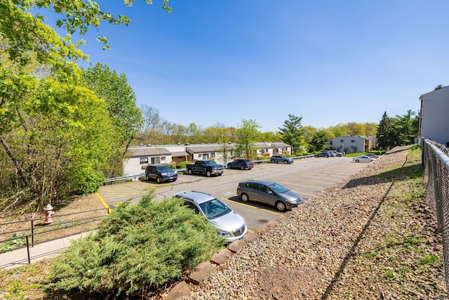 uncovered parking lot featuring fence and a residential view