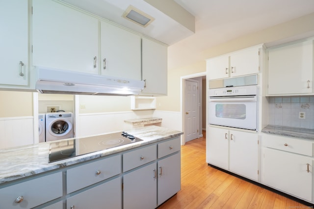 26 Converse Rd, Bolton, CT 06043 - kitchen with white oven, under cabinet range hood, black electric stovetop, separate washer and dryer, and light wood finished floors