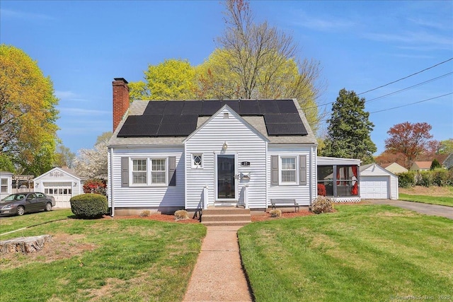 view of front of home with a detached garage, a chimney, solar panels, and a front yard