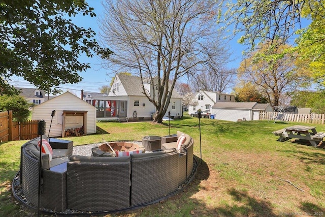 view of yard with fence, an outbuilding, a shed, and an outdoor living space with a fire pit