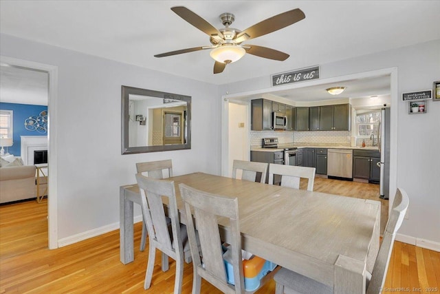dining room featuring baseboards, ceiling fan, and light wood-style floors