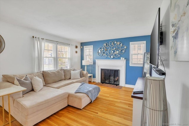 living room featuring baseboards, a fireplace, and light wood-style flooring