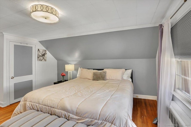bedroom with wood finished floors, baseboards, and lofted ceiling