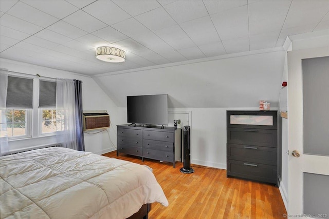 bedroom with light wood-style floors, a wall mounted air conditioner, baseboards, and lofted ceiling