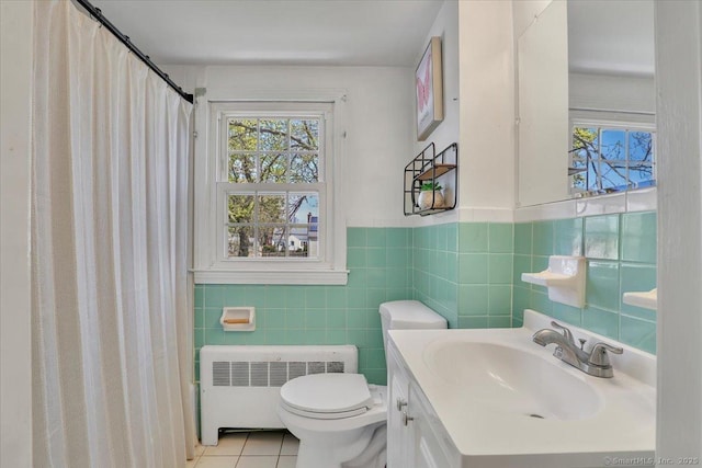 bathroom featuring tile patterned flooring, vanity, toilet, radiator heating unit, and tile walls