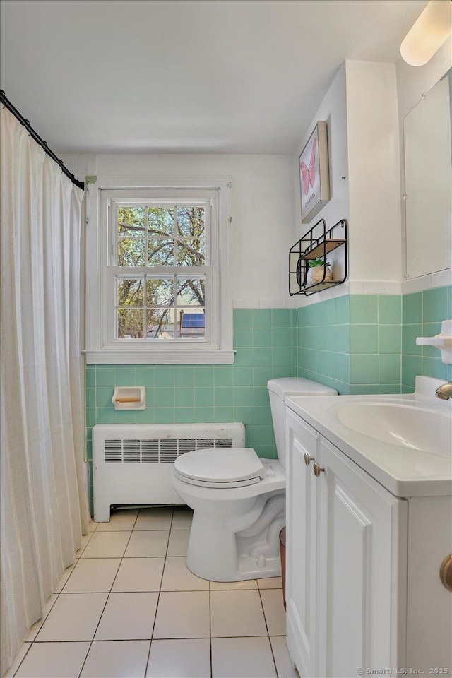 full bathroom featuring tile patterned flooring, vanity, radiator, toilet, and tile walls